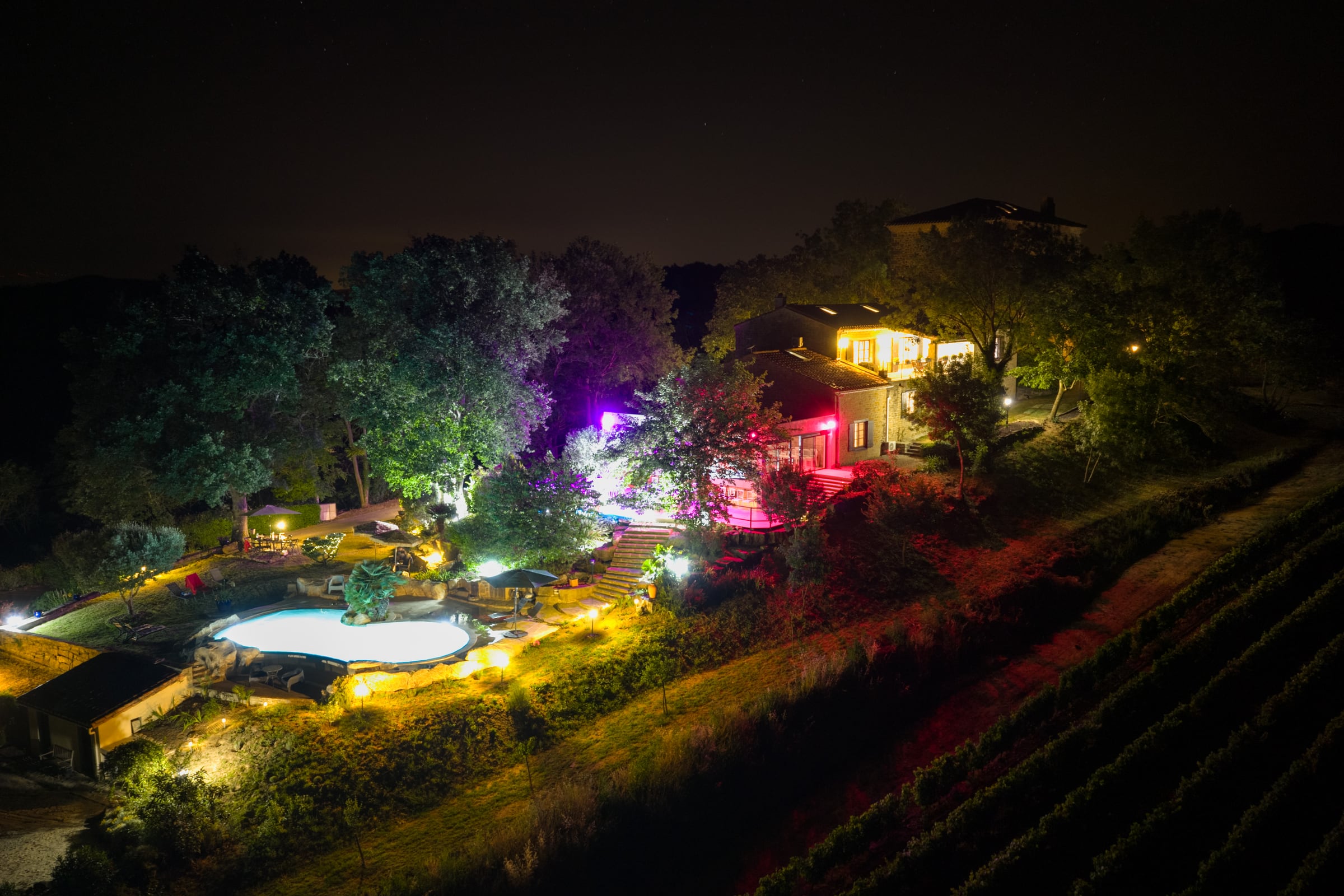 Vue drone nocturne du Château de Tournou illumin&eacute; au c&oelig;ur de son domaine