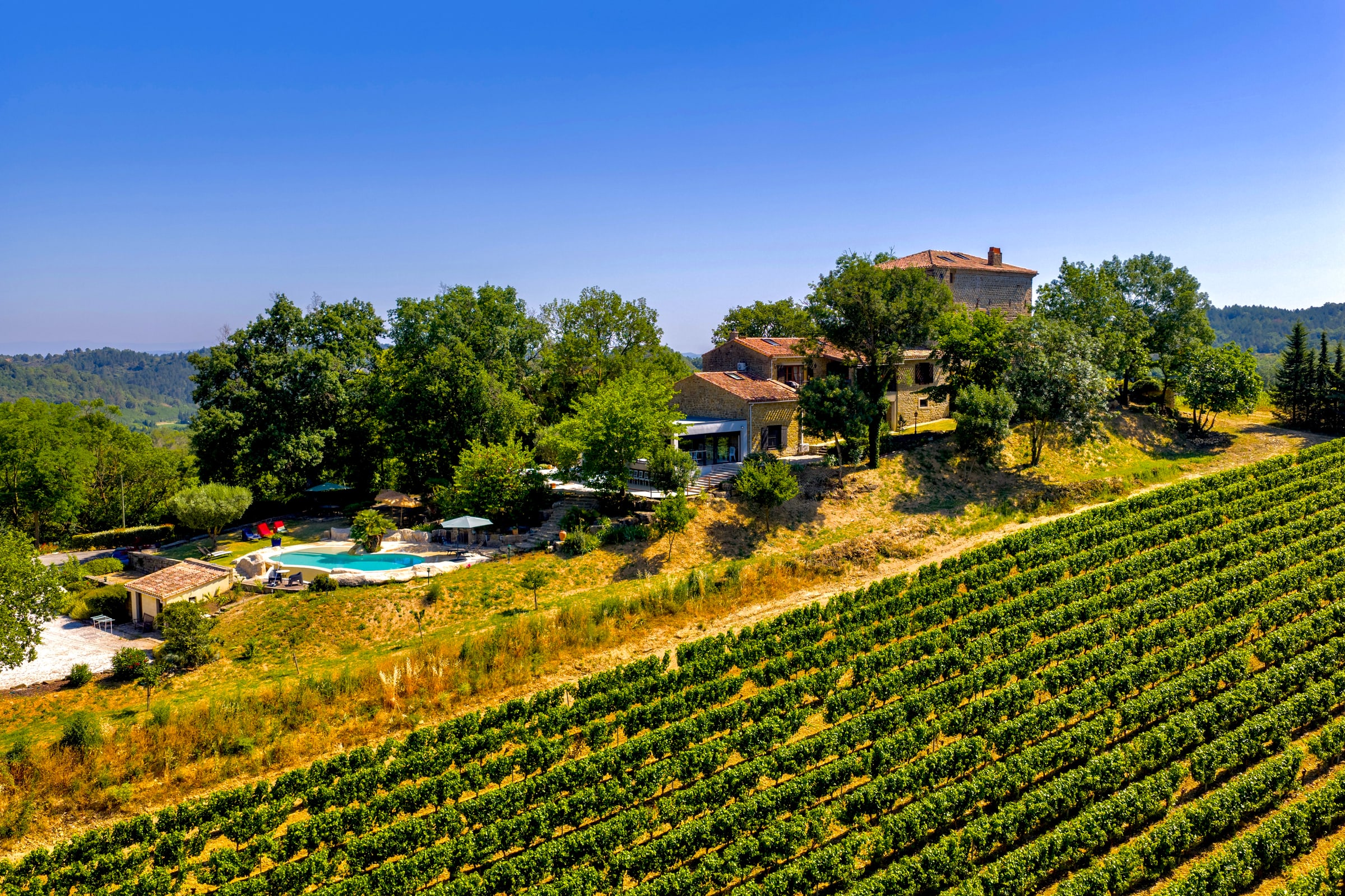 Aerial view of Chateau de Tournou, its private pool and surrounding Limoux vineyards near Carcassonne